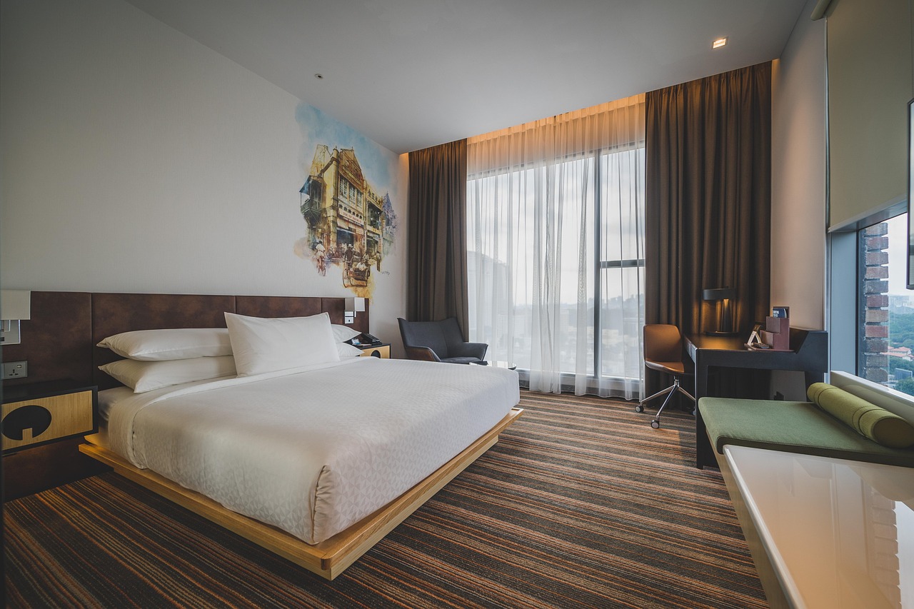 A bespoke hospitality guestroom with a floating wooden desk, integrated lighting, and a comfortable armchair, reflecting personalized custom hotel furniture services.