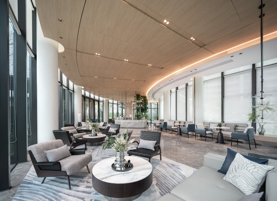 A contemporary commercial reception area furniture layout with a sleek, custom-designed front desk, vibrant artwork, and inviting lounge chairs for guests.