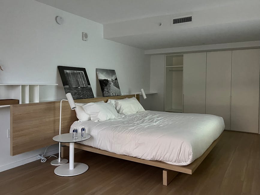 A guest working comfortably at a pull-out desk integrated into a sleek console unit in a contemporary hotel suite, demonstrating multi-functional hotel room furniture.