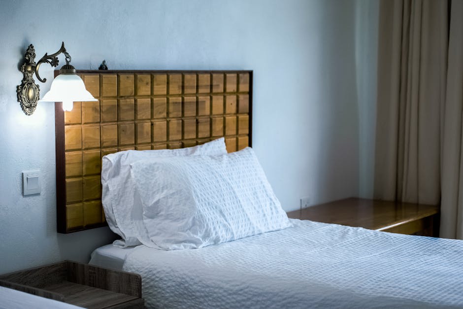 A hotel guestroom with an integrated custom commercial furniture headboard system, featuring built-in lighting and charging ports, made with engineered wood and high-resilience upholstery.