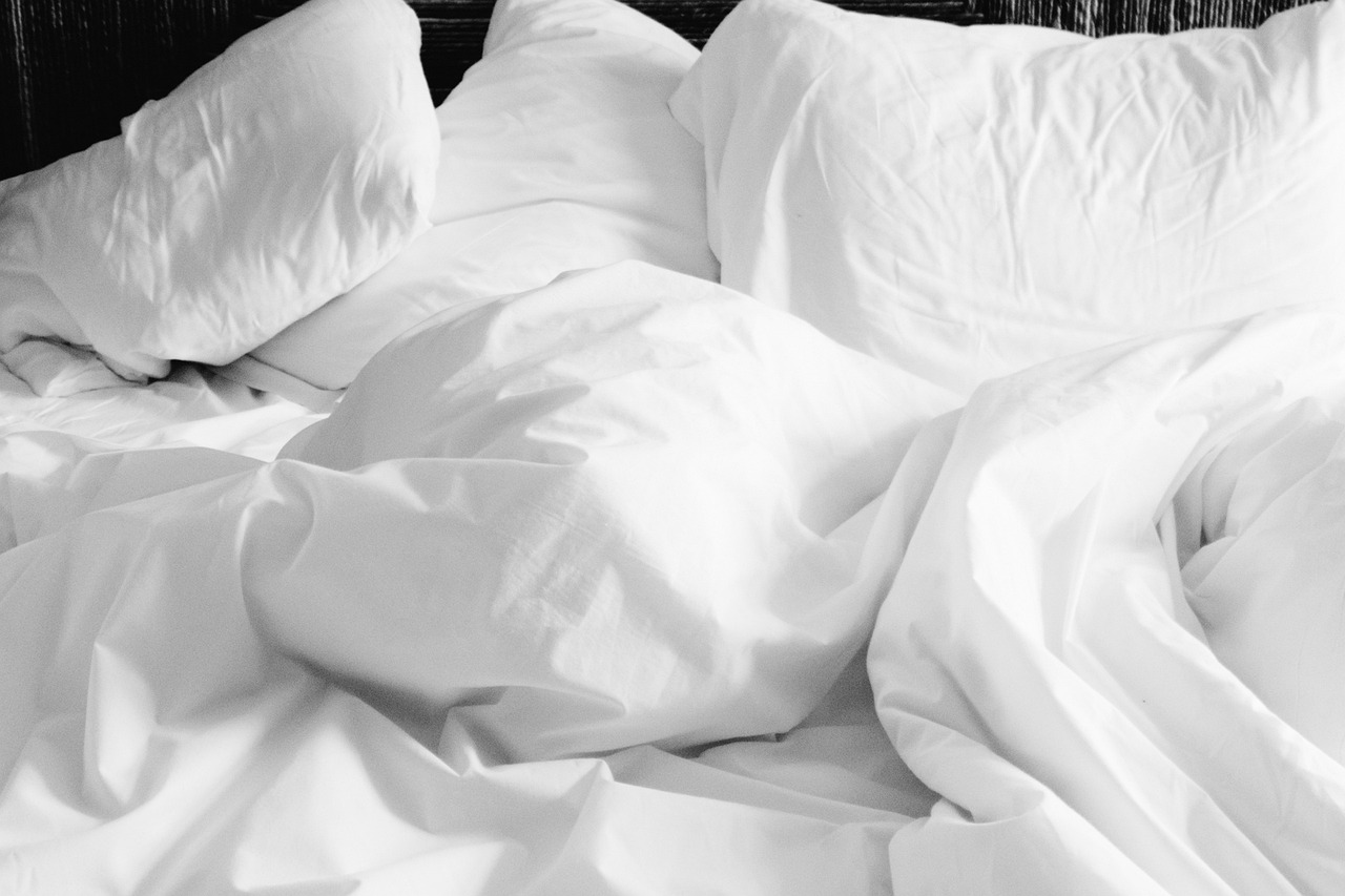 A neatly made hotel bed with a white duvet and multiple pillows, showcasing a comfortable hospitality mattress.