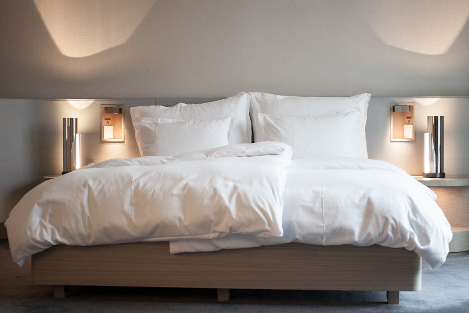 A sleek, modern hotel guestroom bed with a custom upholstered headboard and integrated side tables, showcasing the detailed craftsmanship of hotel bed manufacturers.
