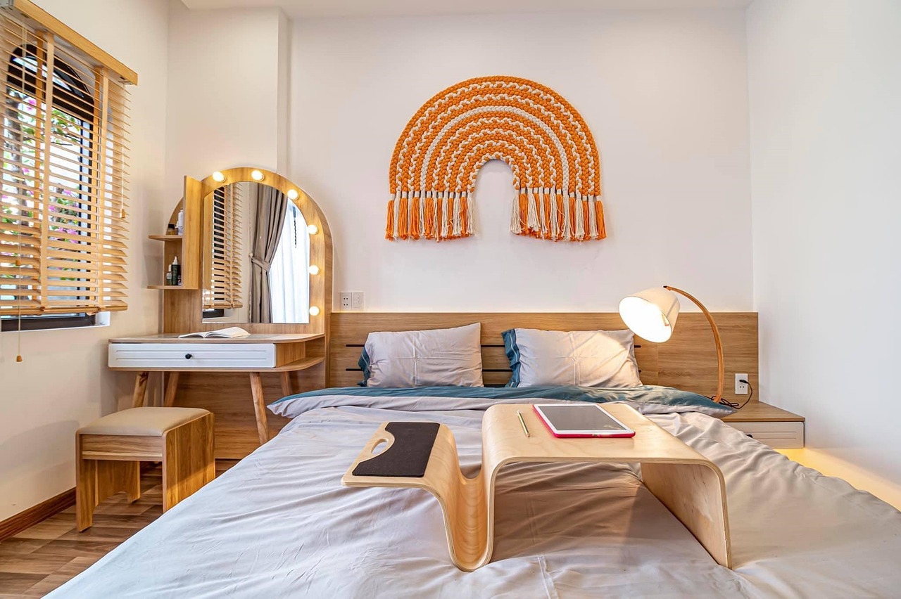 An elegant hotel guestroom with high-end minimalist contract furniture, including a space-saving desk integrated into a wall unit.