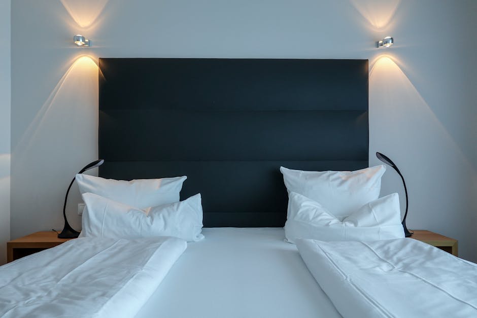 Elegant hotel bedroom featuring a neatly made double bed, modern lighting, and plush pillows.