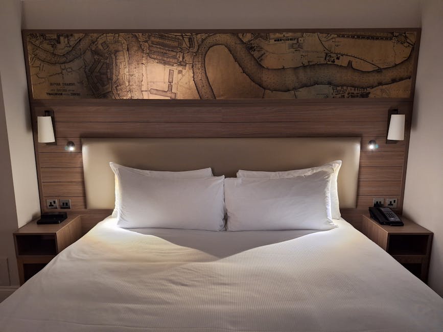 Spacious hotel room in England featuring crisp white bedding and artistic map decor.