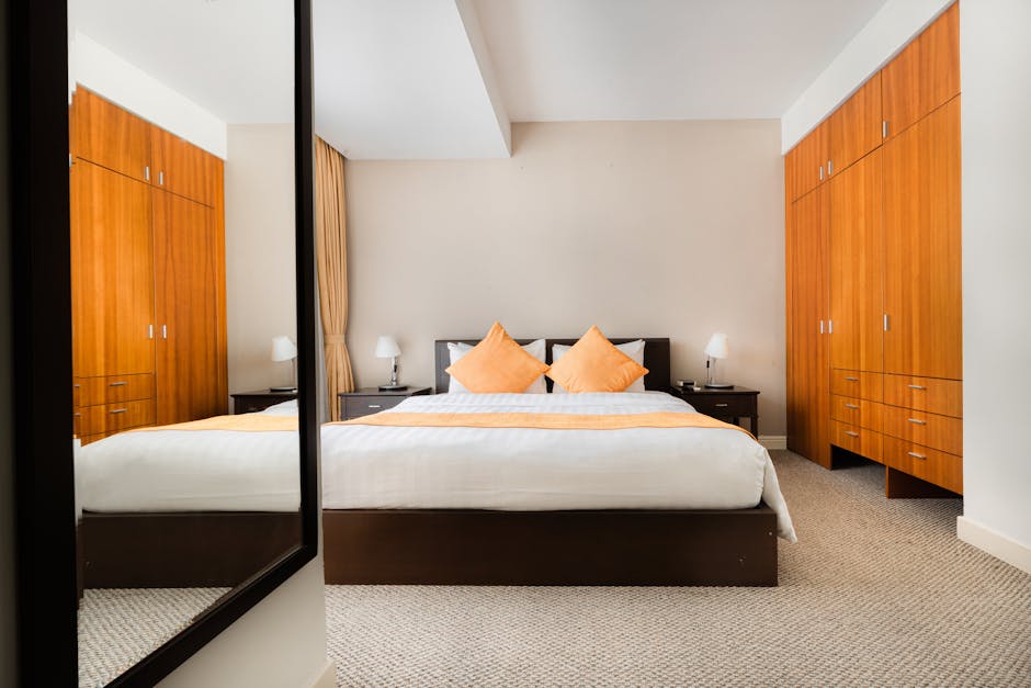 Spacious modern bedroom with elegant decor, featuring a large mirror and stylish wardrobe.