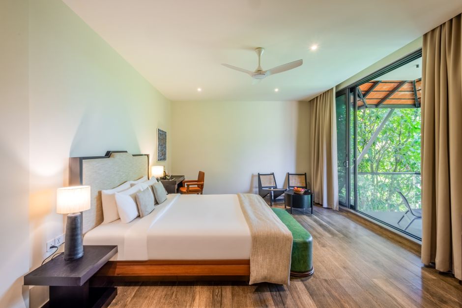 Spacious modern hotel room featuring large windows overlooking lush greenery.