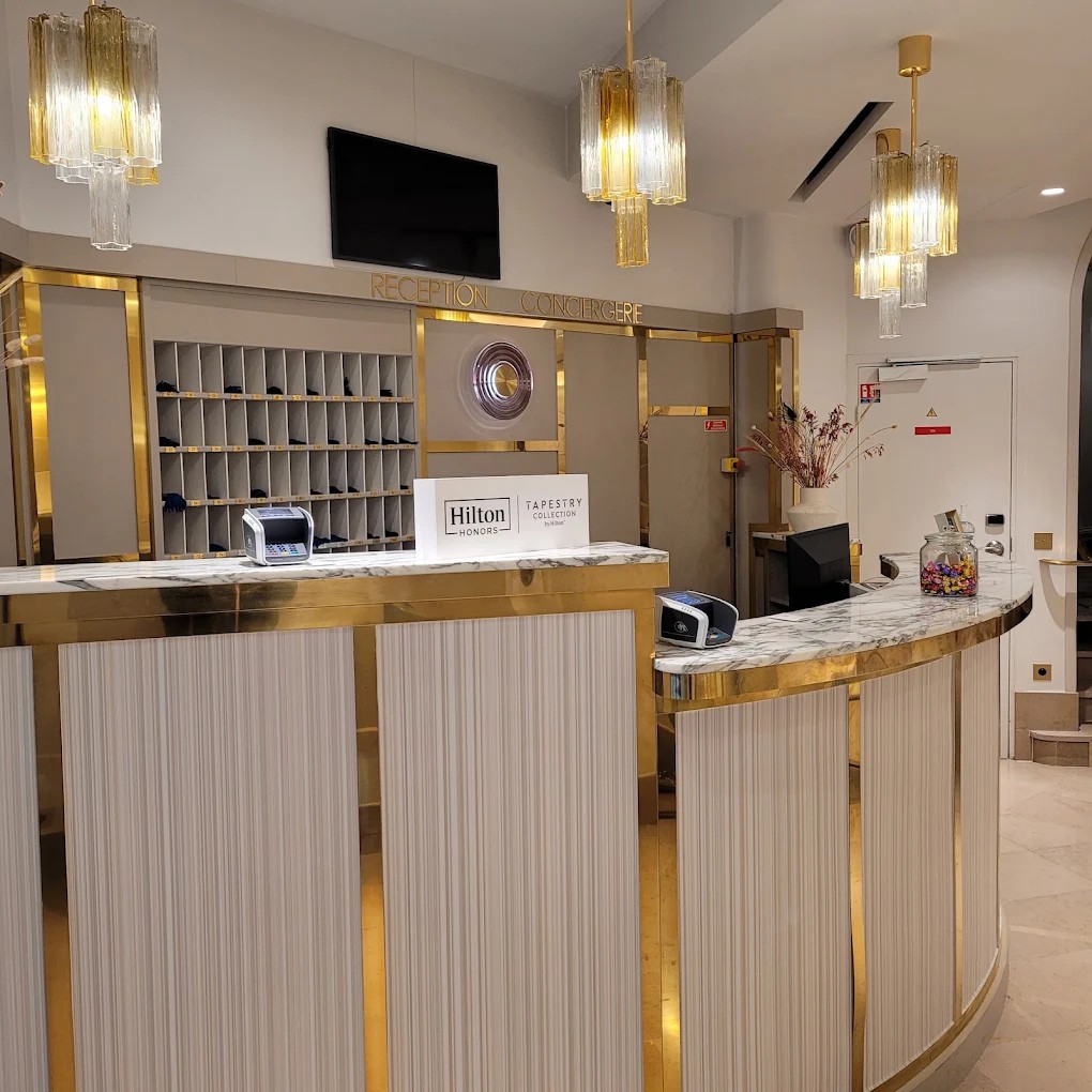 Gold-detailed lobby reception counter at Hotel Camille Paris
