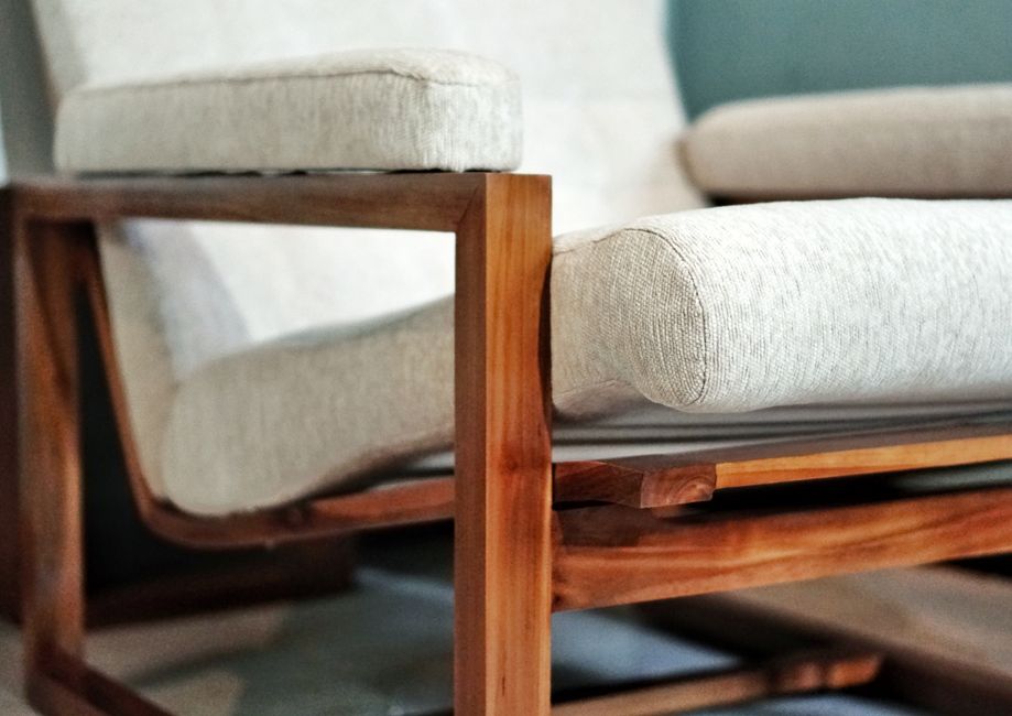 A close-up view of a commercial grade luxury hotel sofa showcasing intricate stitching on a high-performance, stain-resistant fabric, with robust, dark wooden legs.