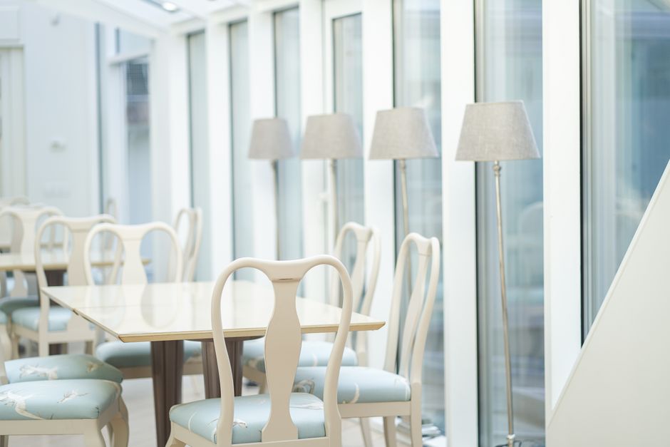 A modern and bright café interior with white chairs, tables, and glass lamps in Riga, Latvia.