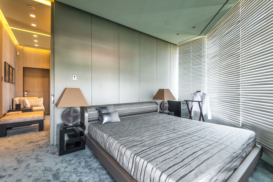 A modern hotel bathroom with a large walk-in shower, natural wood vanity, and subtly textured wall tiles, reflecting restorative hospitality design trends.