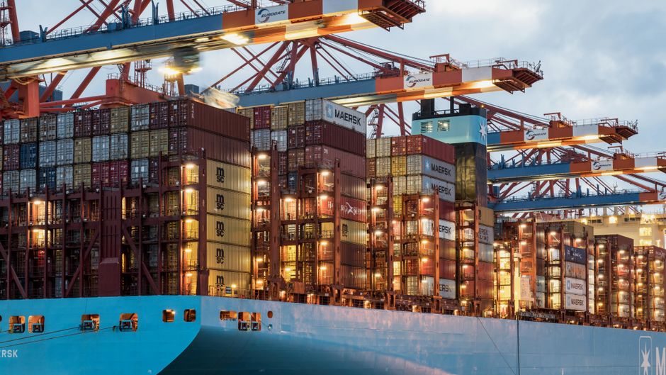 Close-up of a container ship being loaded at a bustling port, symbolizing the complex process of shipping hotel furniture to Africa.