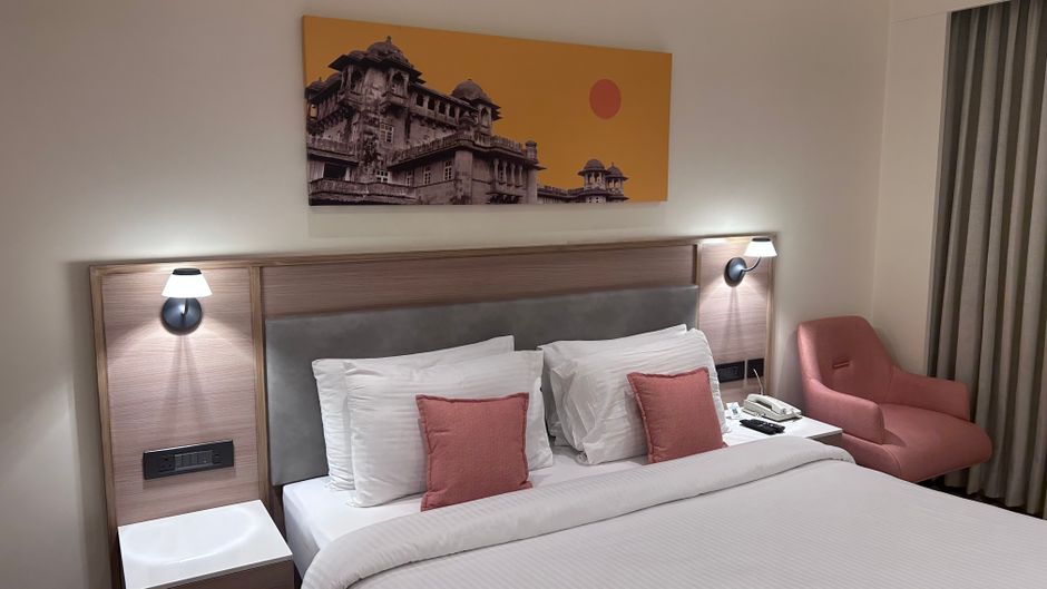 Factory mock-up room showing complete hotel guestroom furniture setup with compliance labels