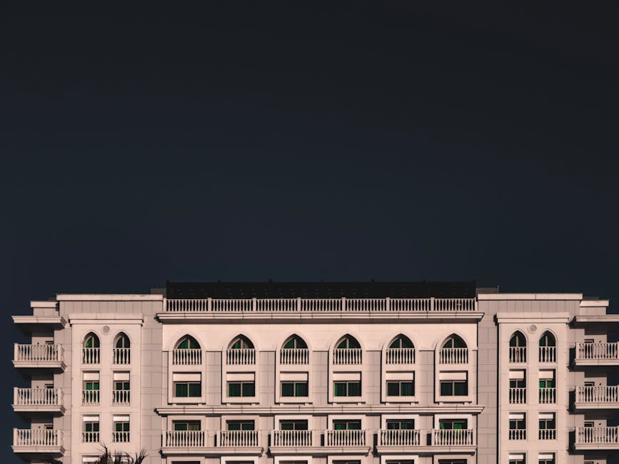 Minimalist image of a classic hotel facade against a dark dramatic sky, highlighting urban architecture.