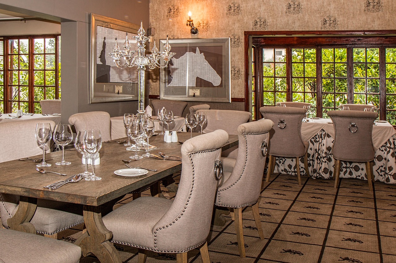 Hotel staff efficiently cleaning restaurant dining chairs and tables in a well-lit dining area, highlighting the importance of easy-to-maintain hotel restaurant furniture.