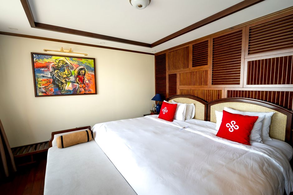 Modern hotel room featuring a large bed, vibrant artwork, and wooden accents, ideal for relaxation.