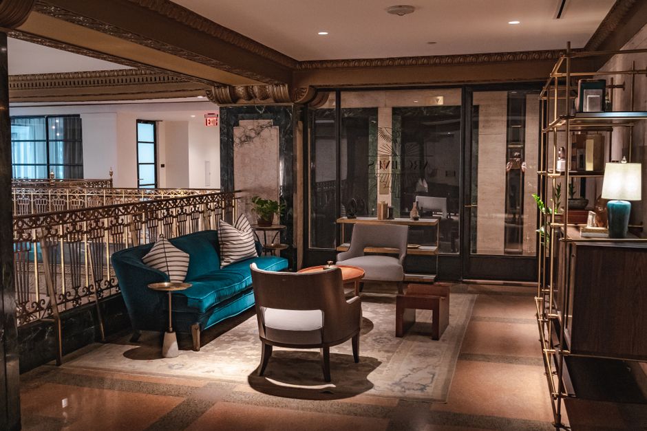 Sophisticated hotel lounge featuring velvet couch, armchairs, and elegant decor in cozy lighting.