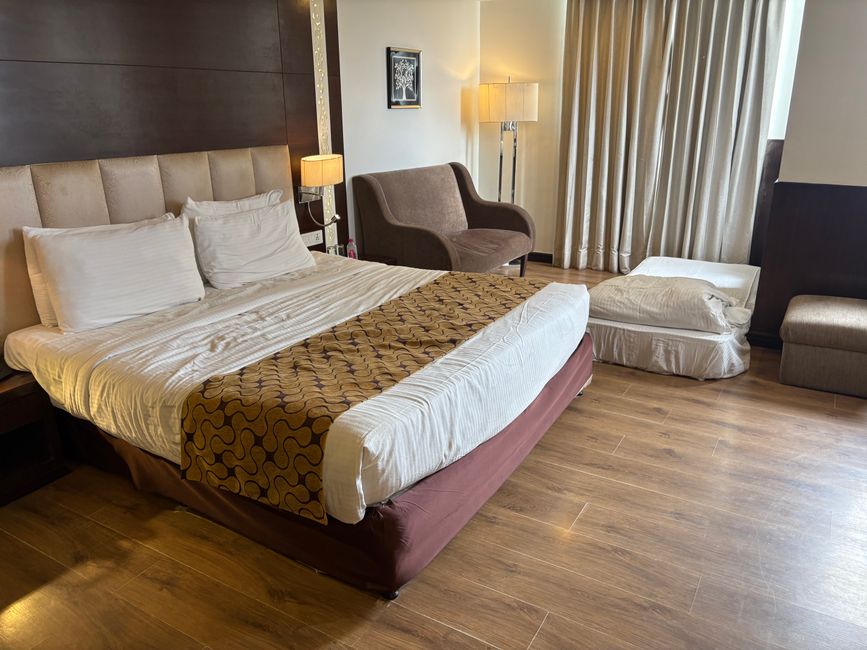 A chic hotel room featuring a comfortable bed, modern furniture, and soft lighting.