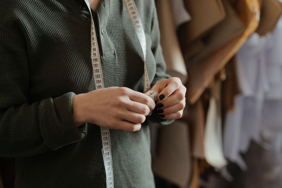 Close-up of a person using a measuring tape in a sewing studio, focusing on patterns and precision.