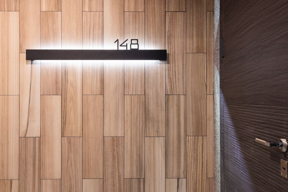 Illuminated number of room hanging on wall made of wooden panels near door in modern hotel