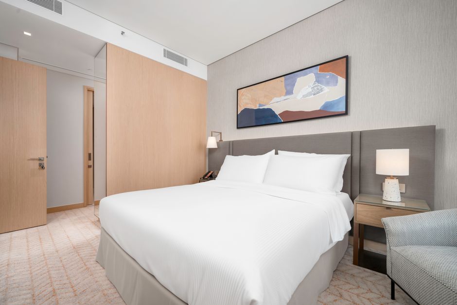 Spacious modern hotel room interior with a comfortable bed and elegant decor.